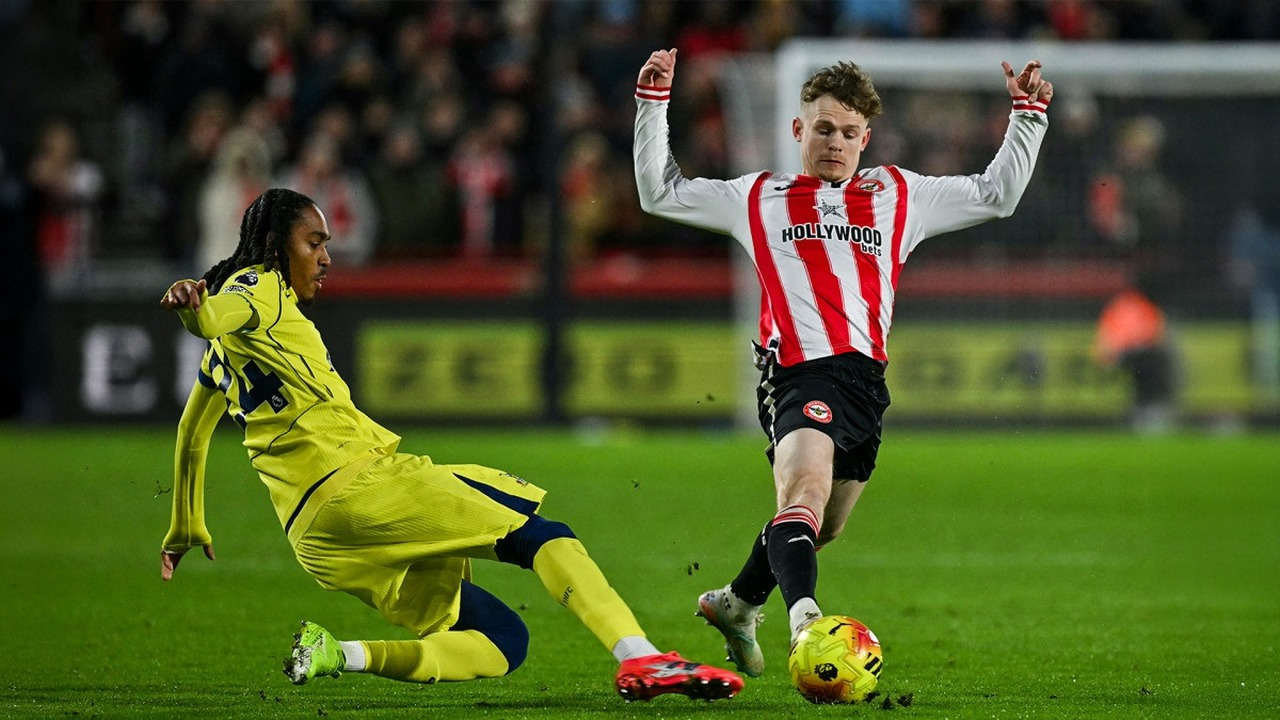 A Tottenham player challenges a Brentford player for the ball